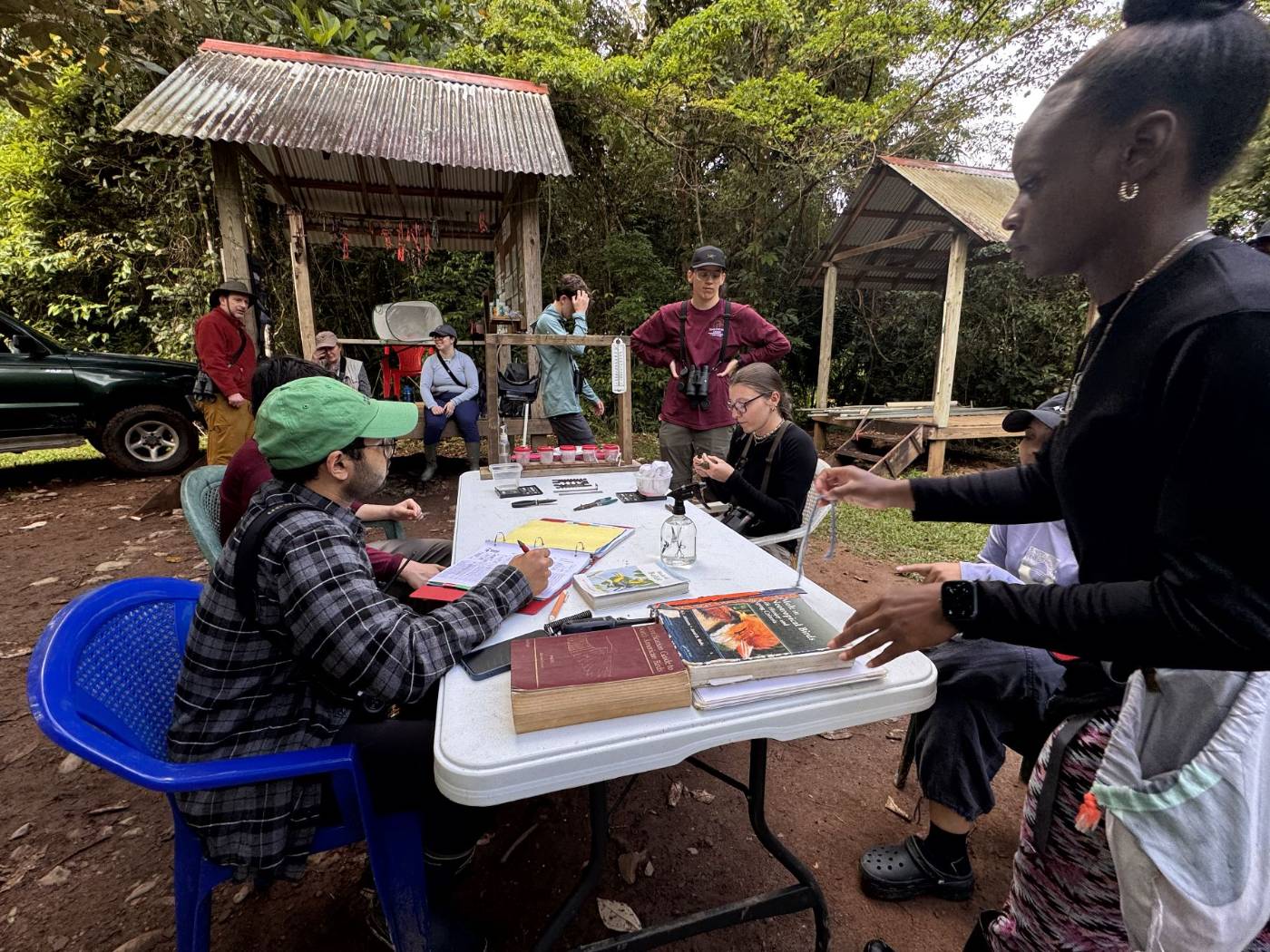 Students and station biologists recording bird data at a field table with identification guides