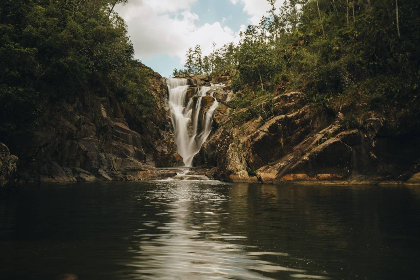 A waterfall pouring into a dark pool in Mountain Pine Ridge Forest Reserve