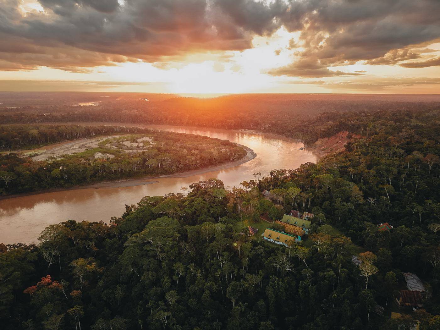 Aerial view at sunset of the Los Amigos station buildings in the forest beside a bend of the Madre de Dios River
