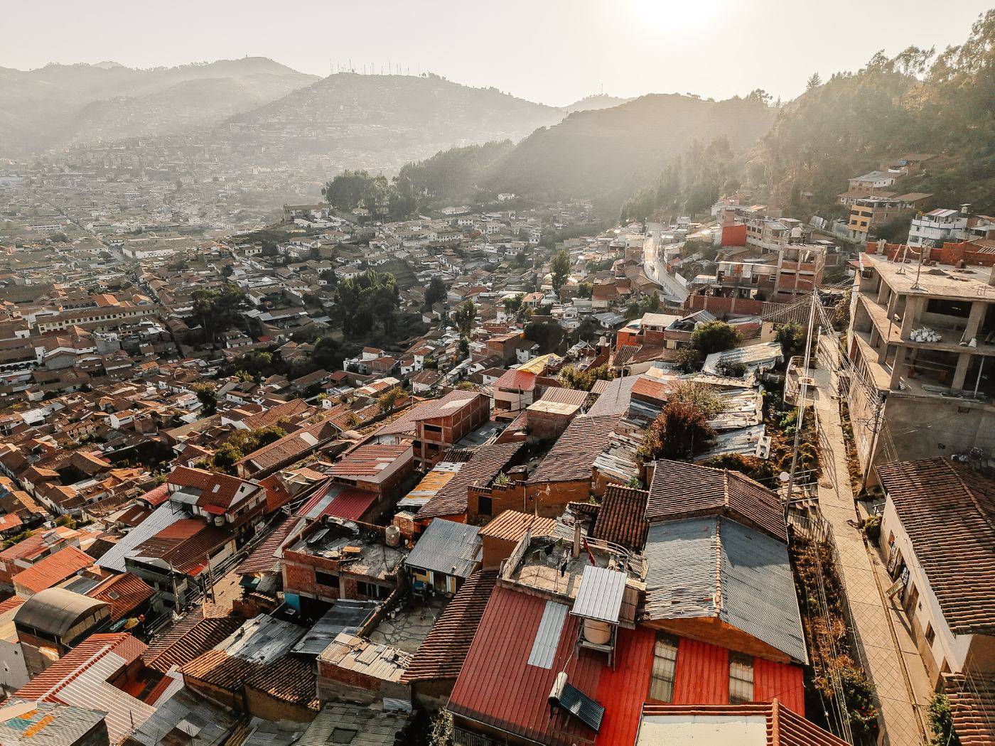 Aerial view of Cusco rooftops climbing the hillsides in hazy morning light