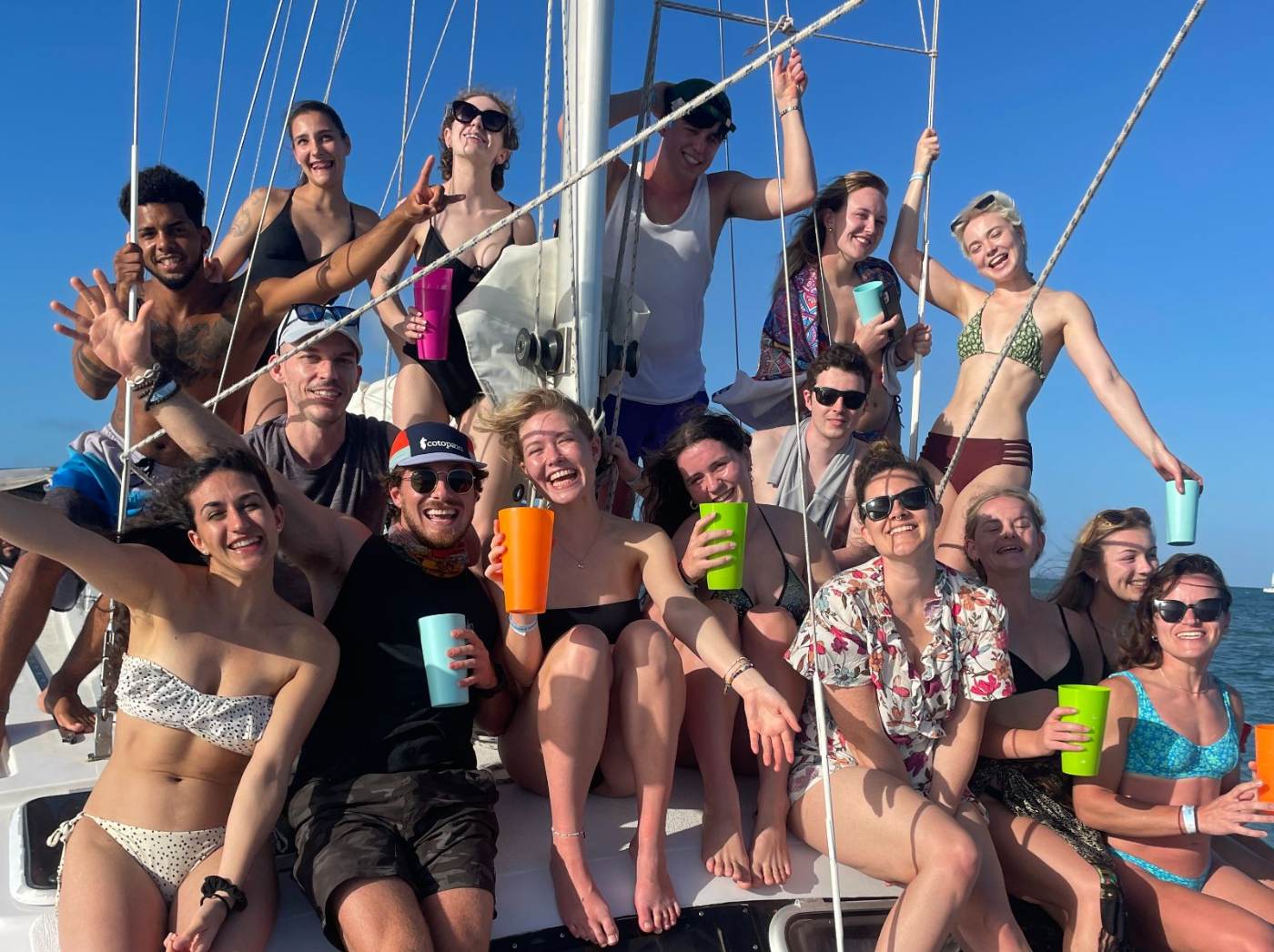 A student group gathered on the deck of a sailboat under a clear sky