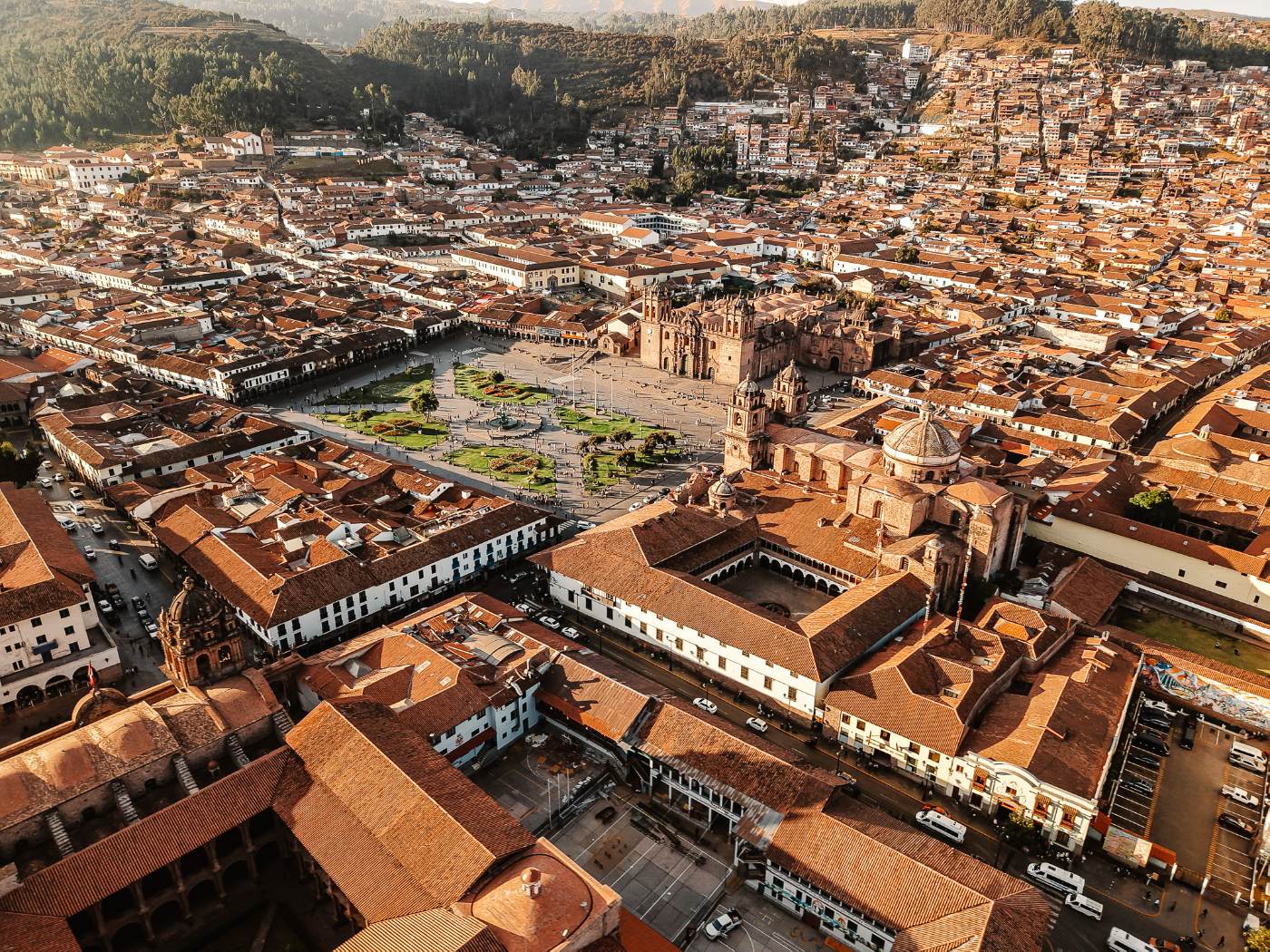 Aerial view of Cusco's Plaza de Armas and cathedral surrounded by red tile roofs in late light