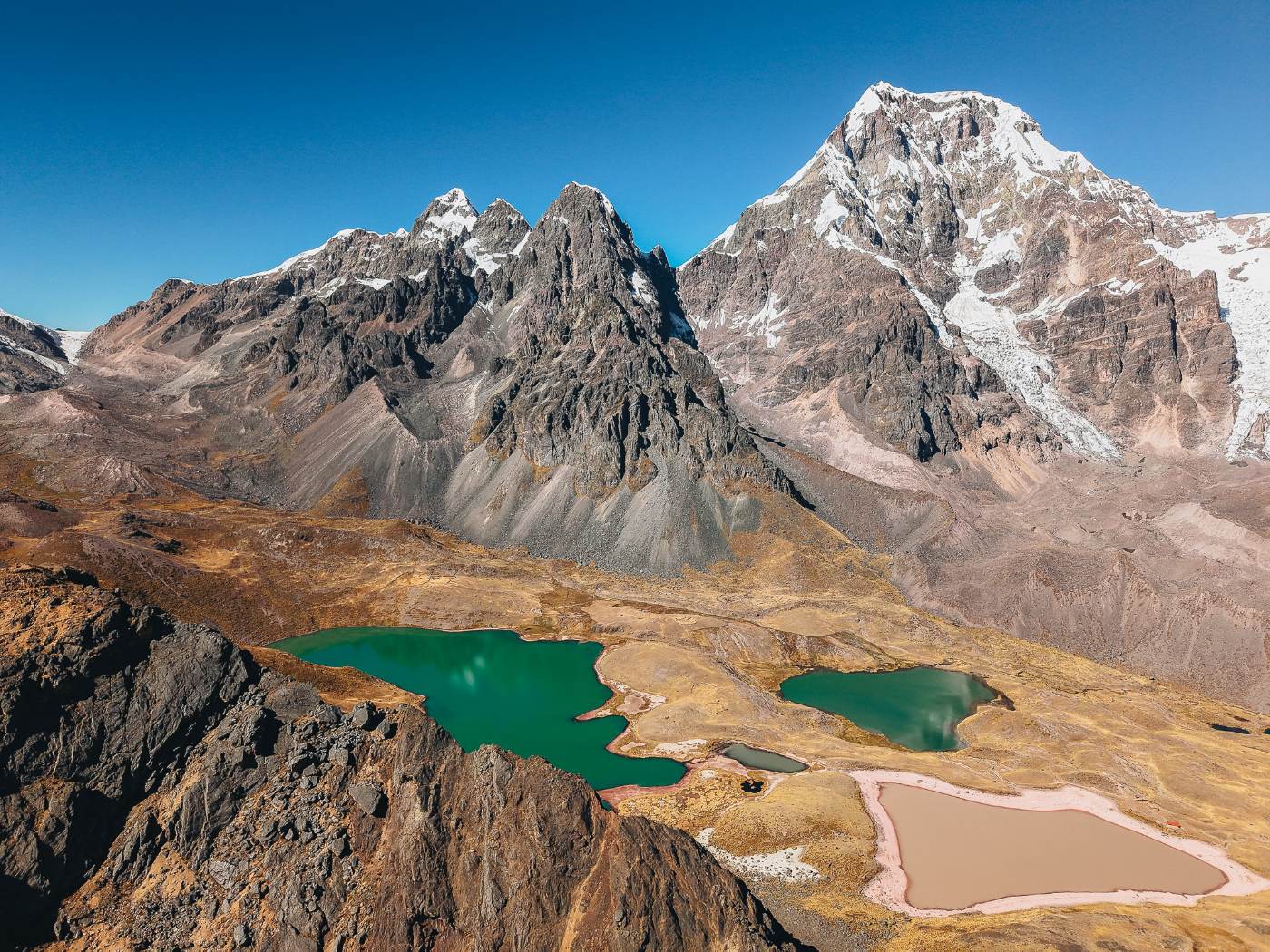 Turquoise and rust-colored glacial lakes beneath a snow-capped Andean peak