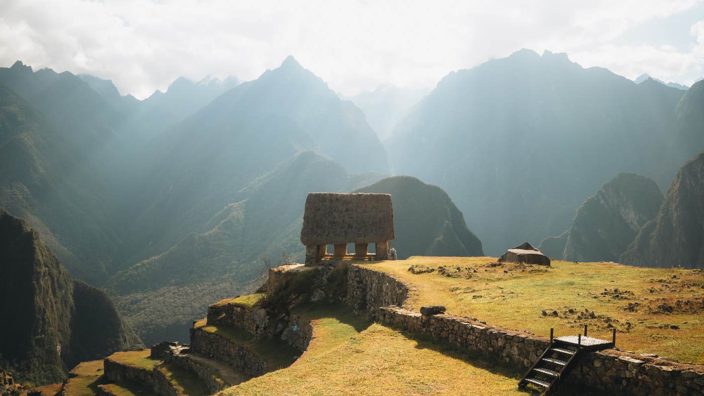 The thatched guardhouse above Machu Picchu against hazy green peaks