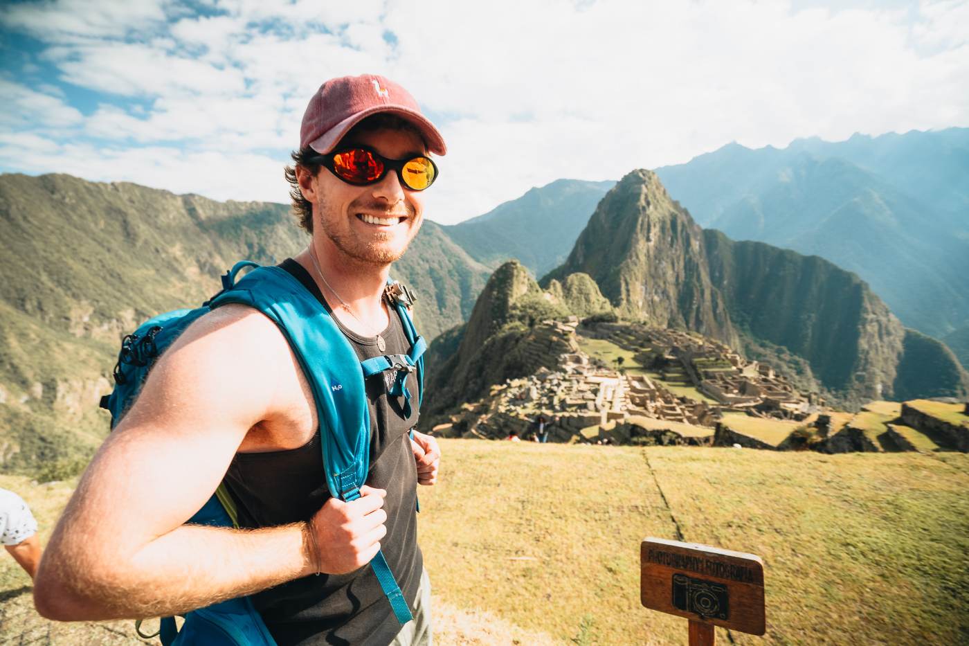 A smiling traveler in sunglasses at the Machu Picchu overlook